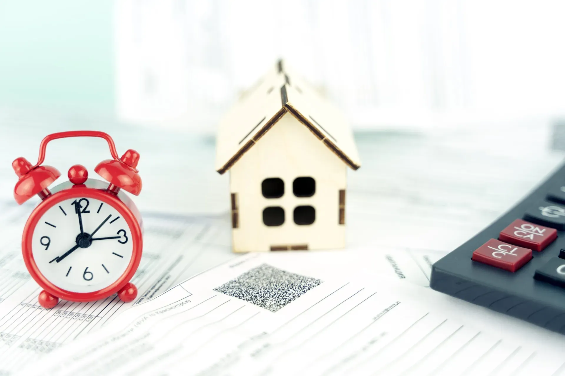 alarm clock wooden house and calculator, the concept of paying utility bills