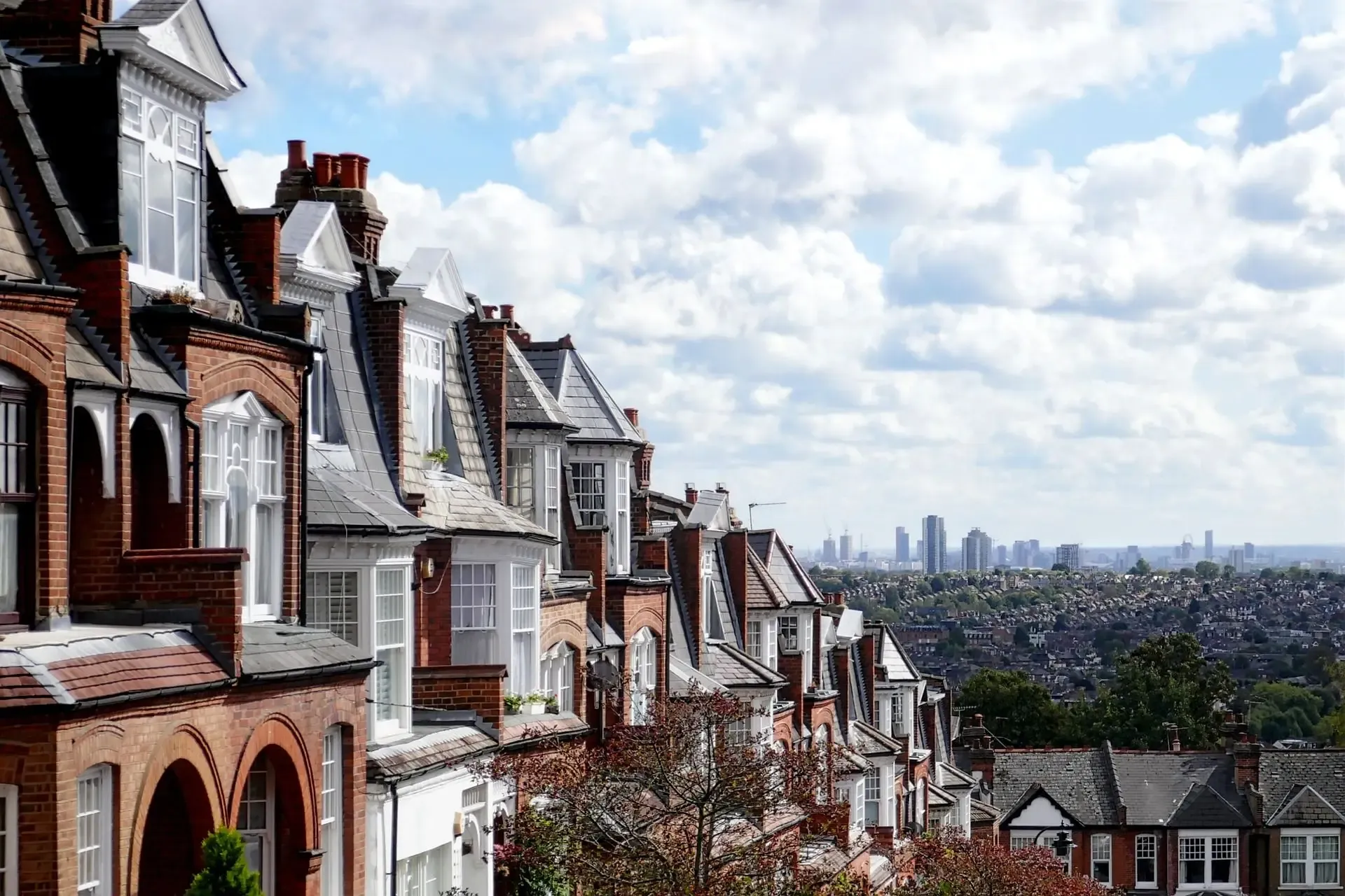 A cityscape of London houses with a background of the city, filled with skyscrapers of businesses.