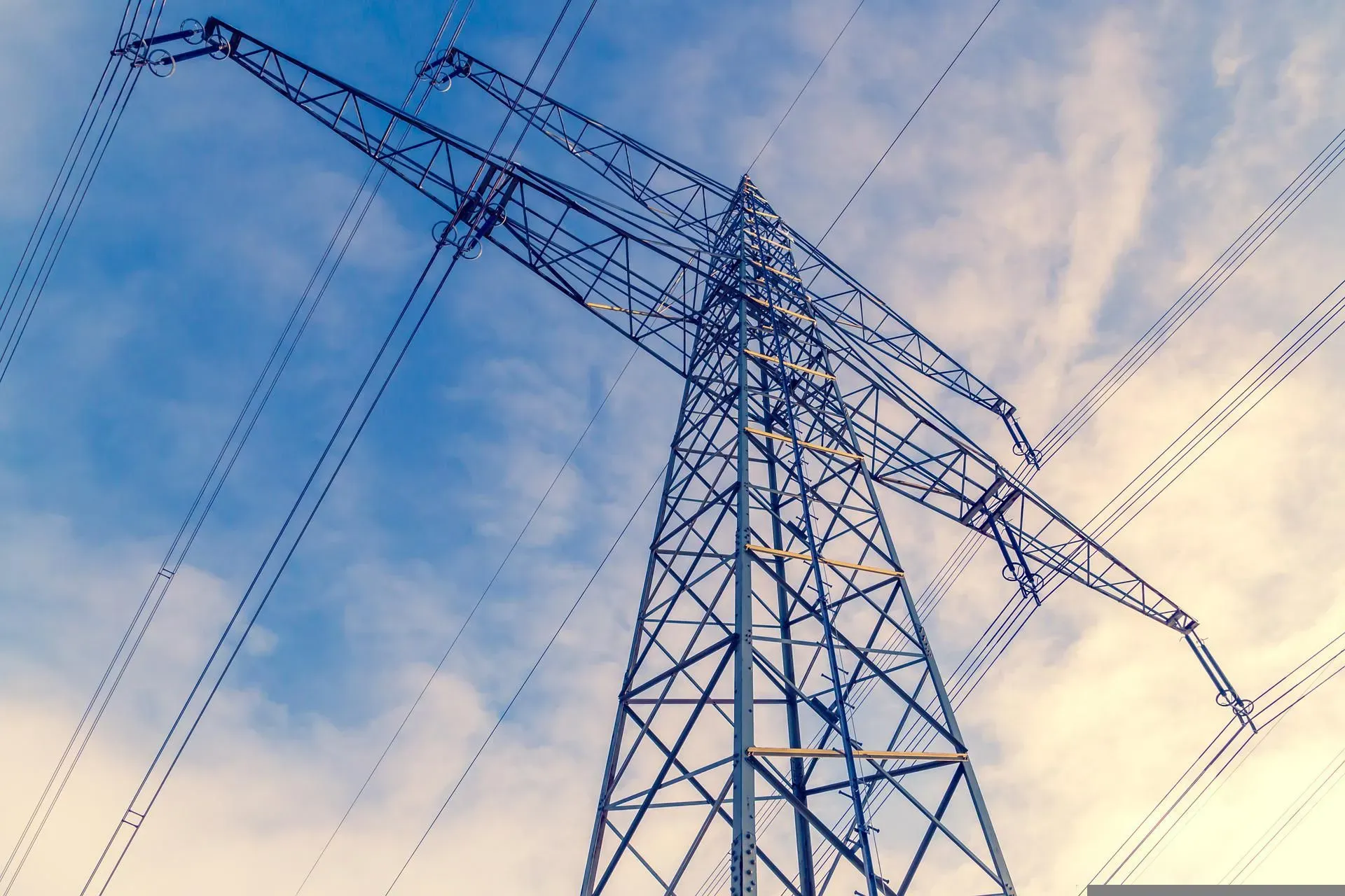 An electricity pylon in front of a cloudy sky.