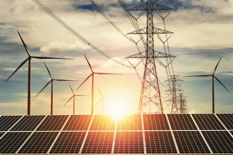 Sunset image of electricity pylons, wind turbines, and solar panels