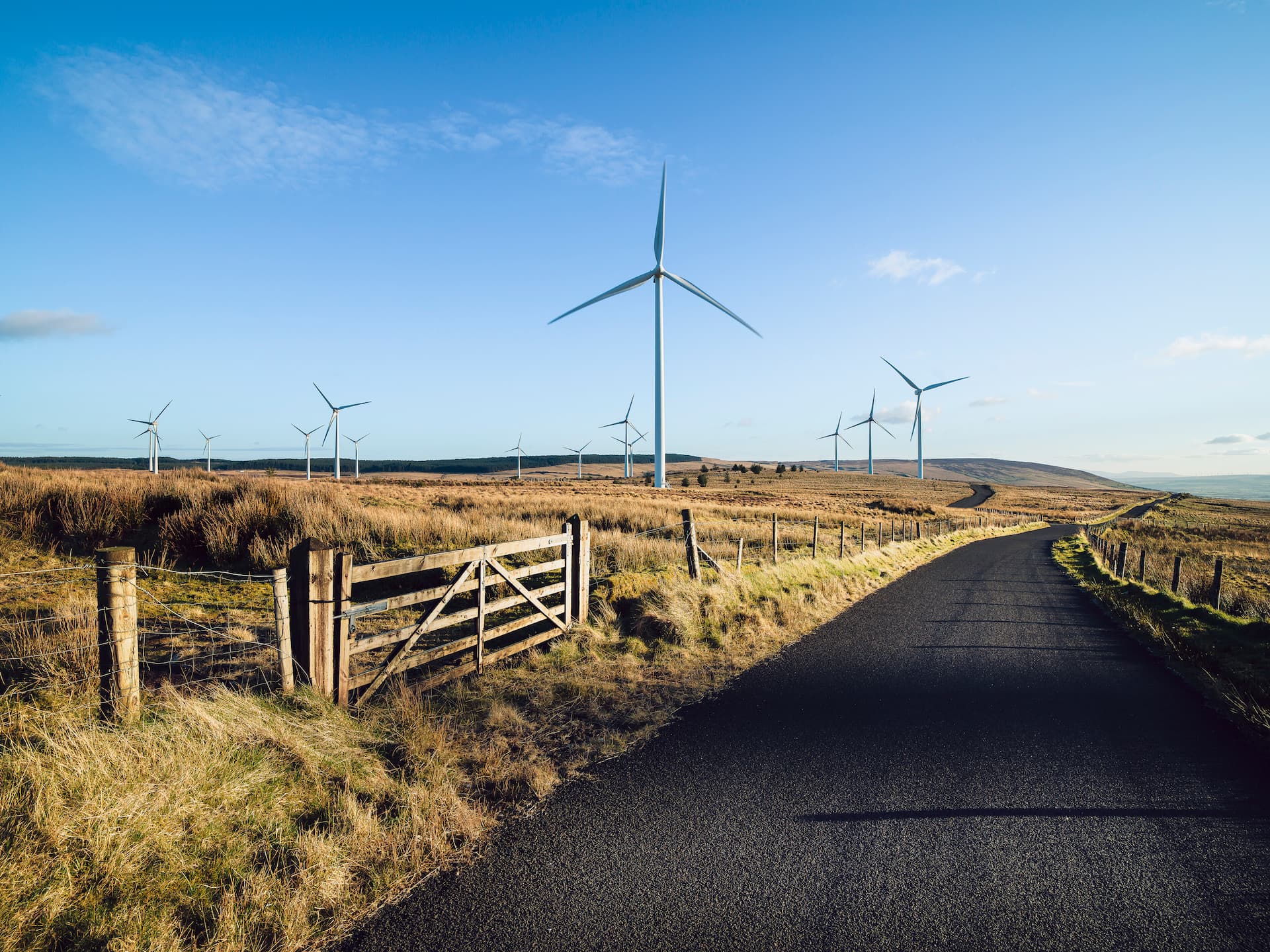 Wind turbines on rural country road against blue skyu